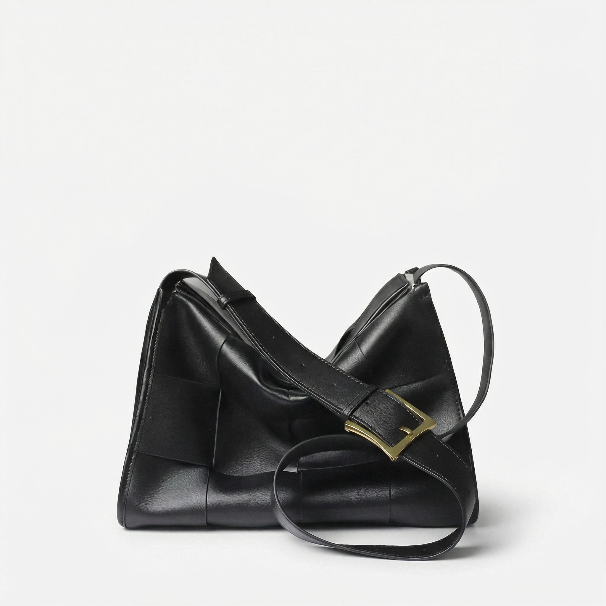 Black leather handbag with a gold clasp on a light gray background