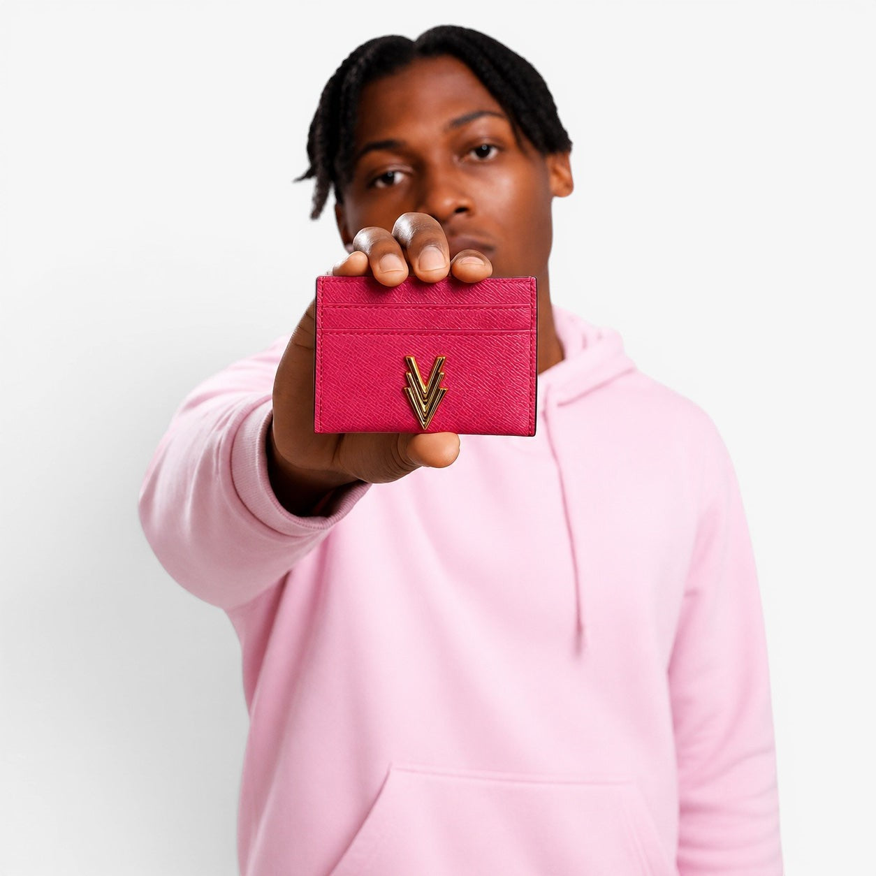 Person holding a pink cardholder with a gold logo against a light gray background
