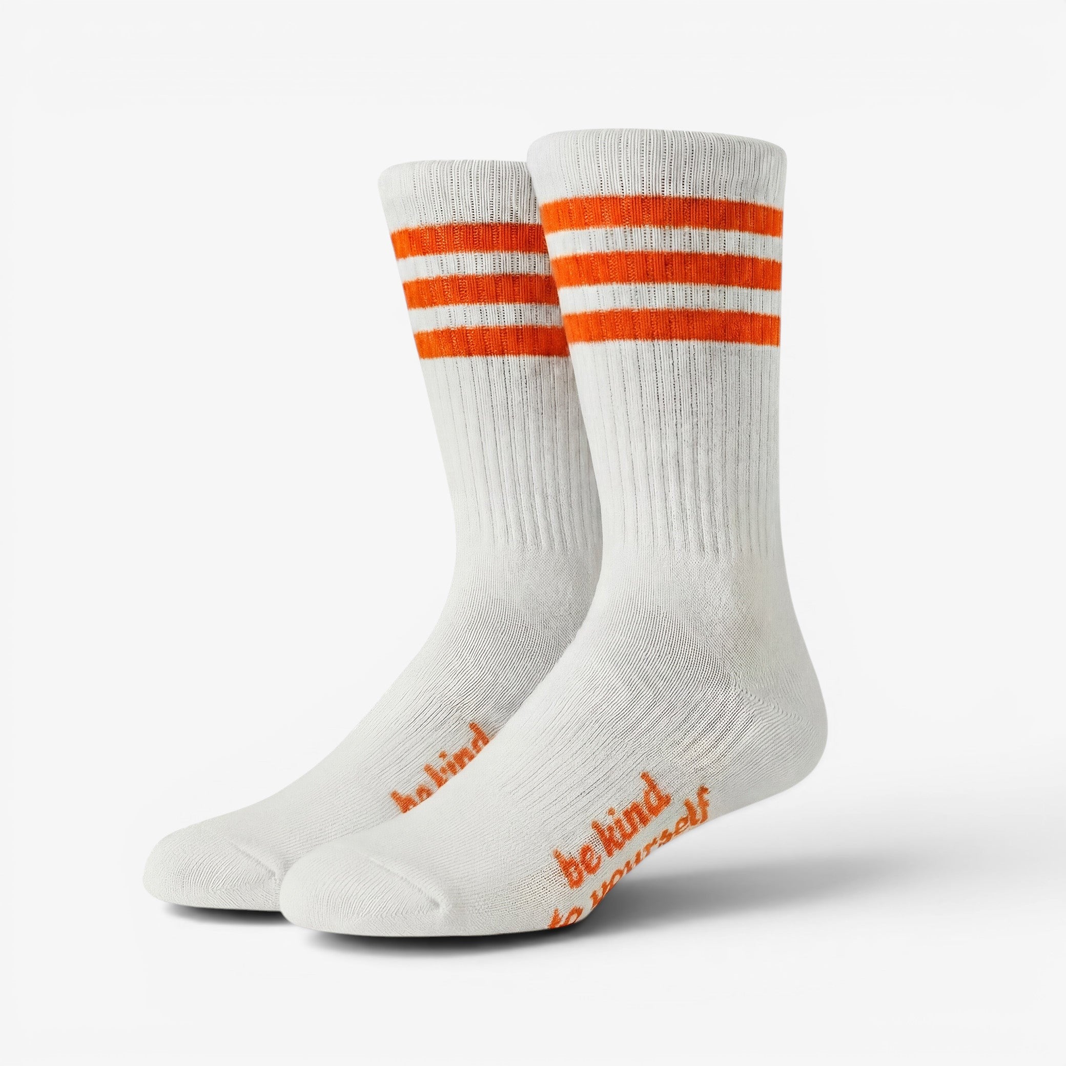 White socks with orange stripes and 'be kind' text on a white background