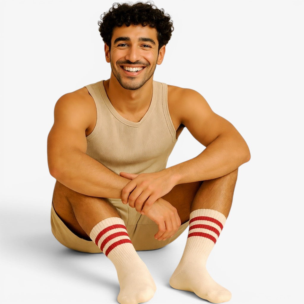 Man wearing a beige tank top and white socks with red stripes on a beige background
