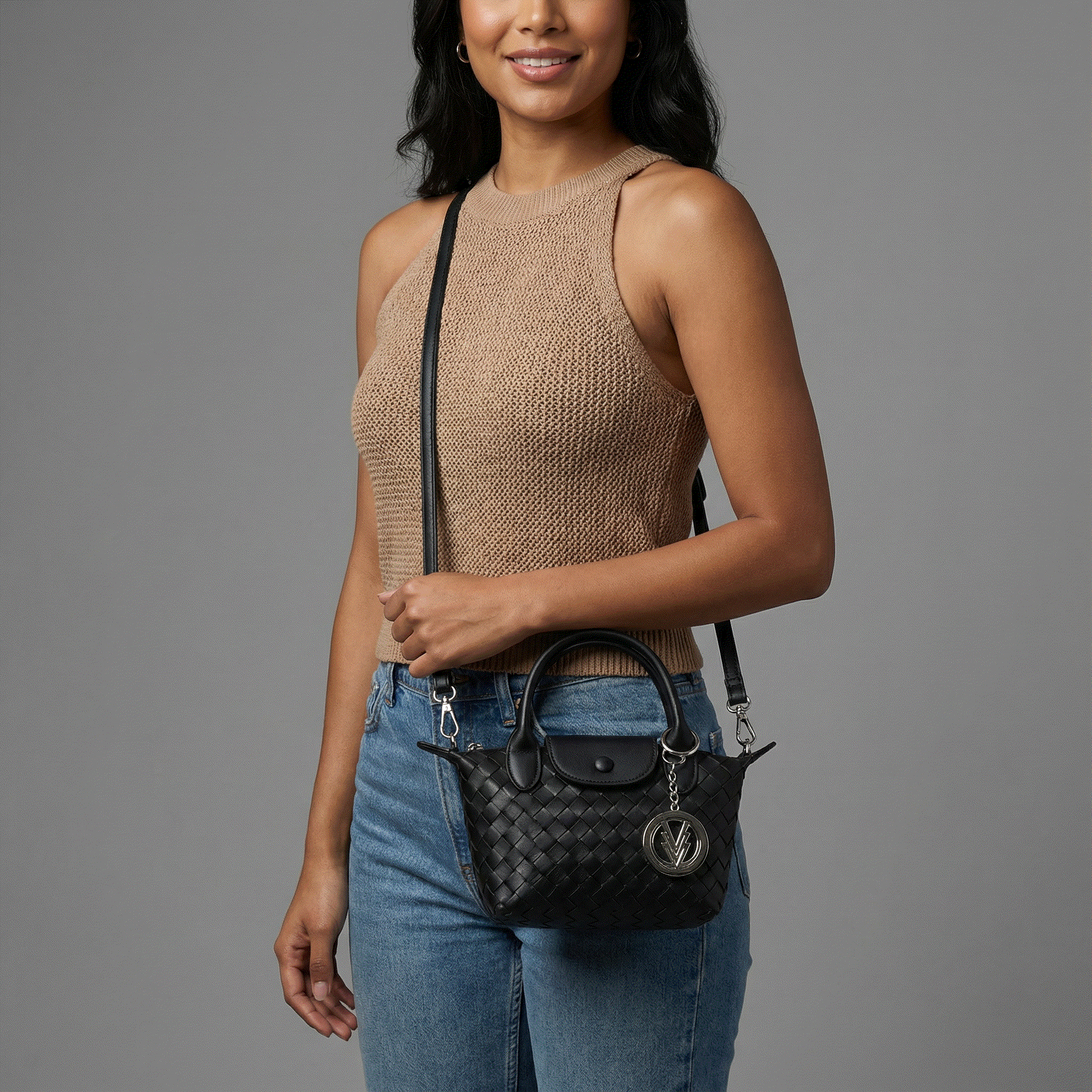 Woman holding a black handbag with a gray background