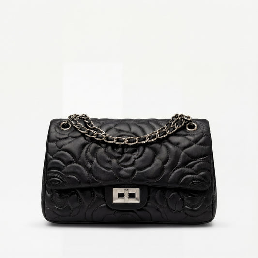 Black quilted handbag with a chain strap on a white background