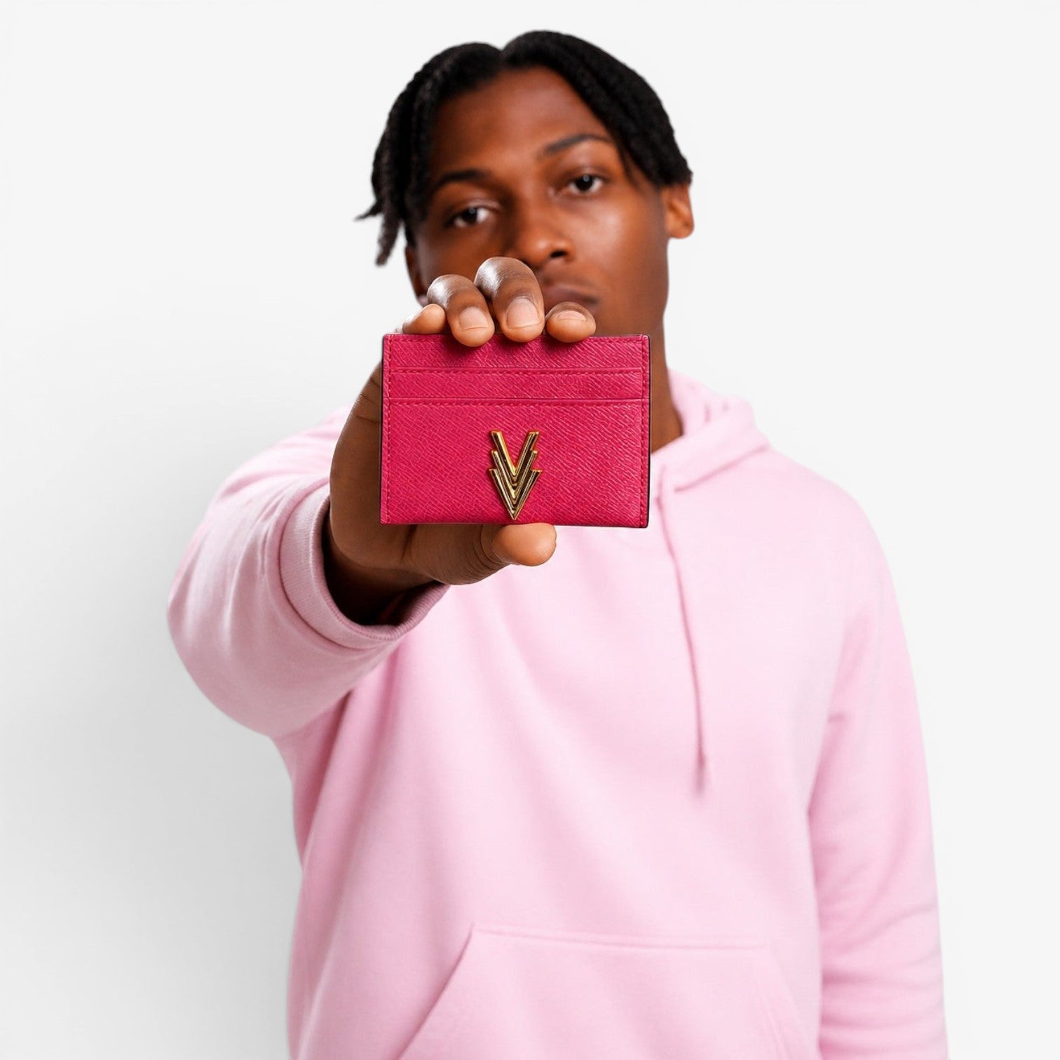 Person holding a pink cardholder with a gold logo against a light gray background