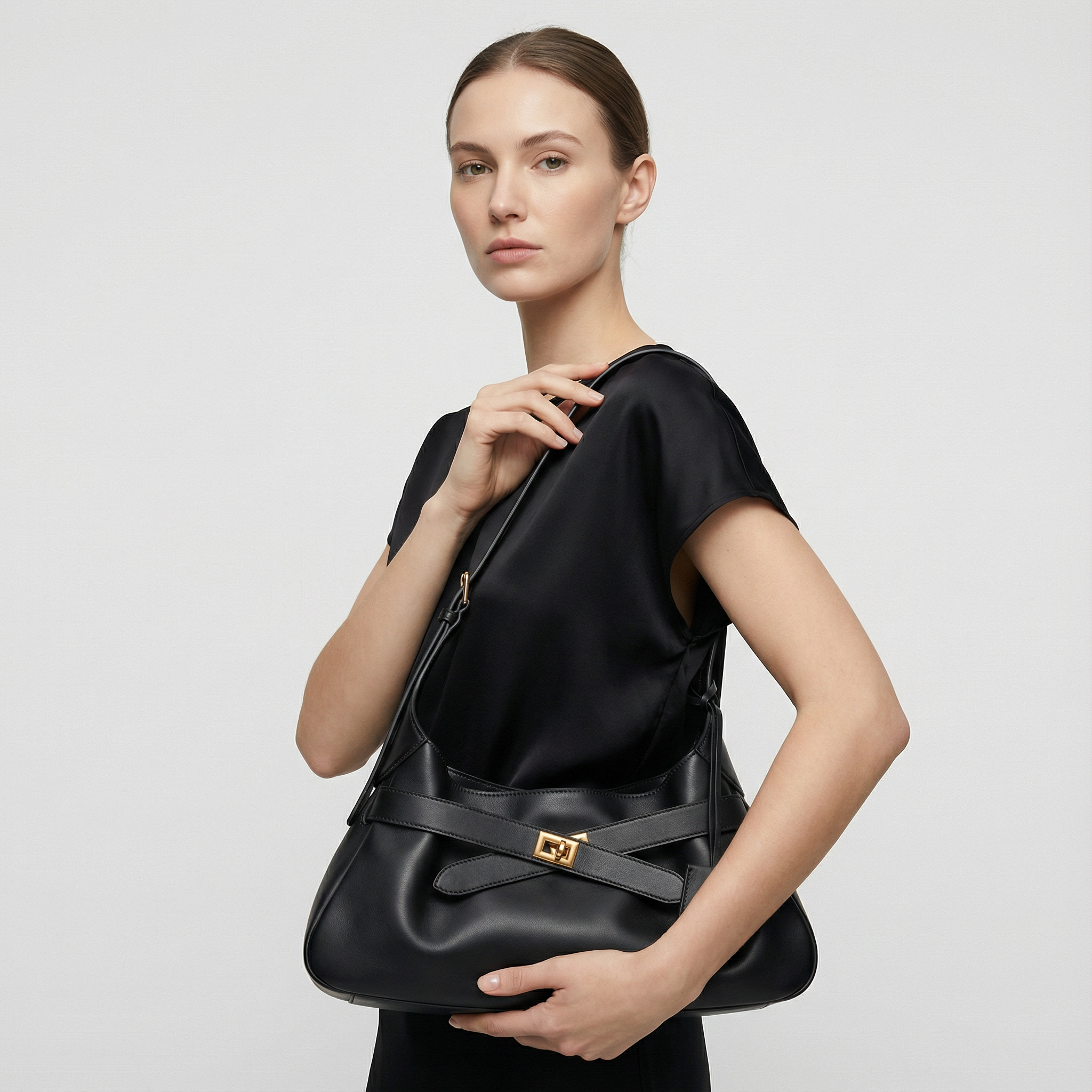 Woman holding a black handbag against a plain background