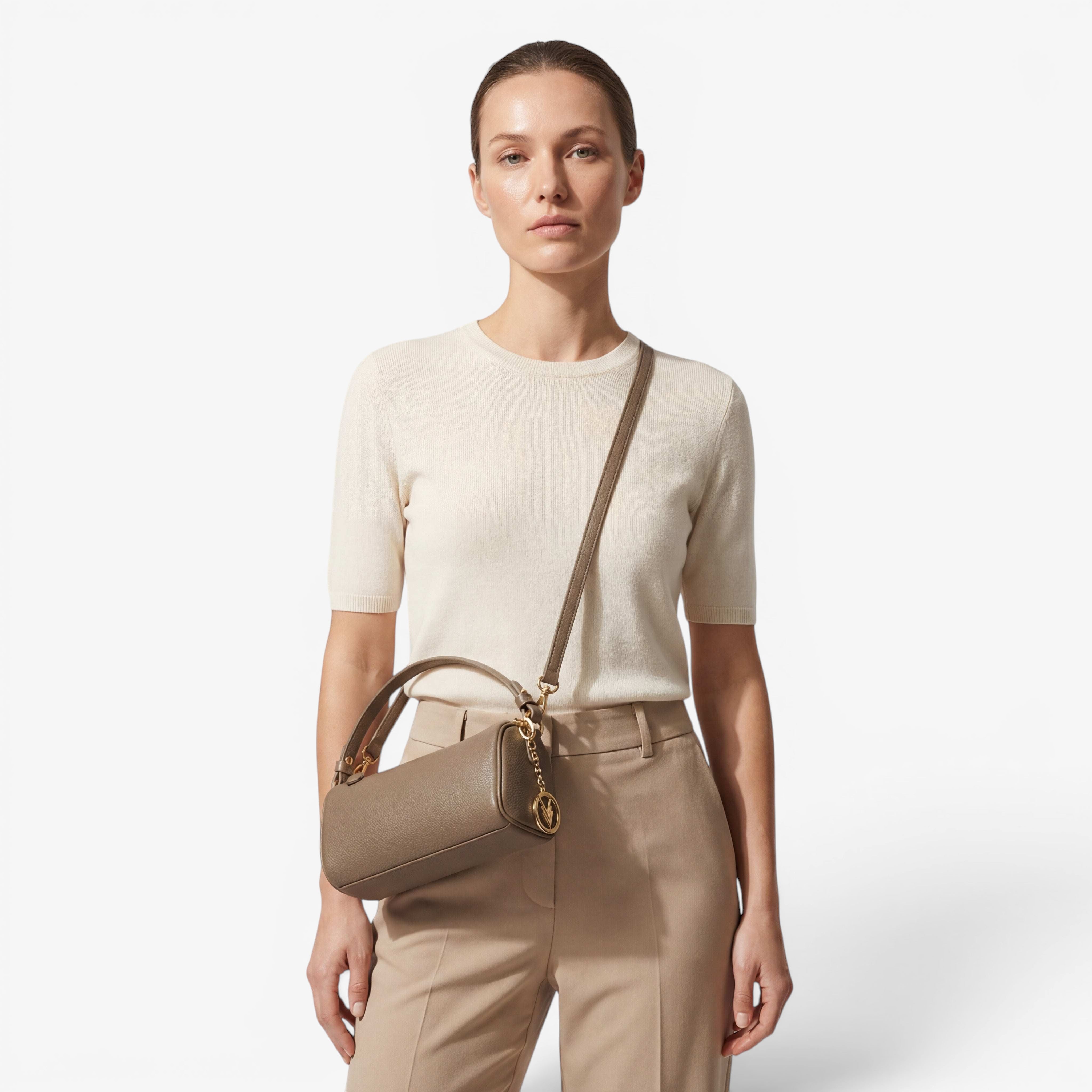 Woman holding a beige handbag against a plain background