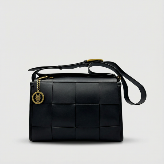 Black woven handbag with gold accents on a light gray background