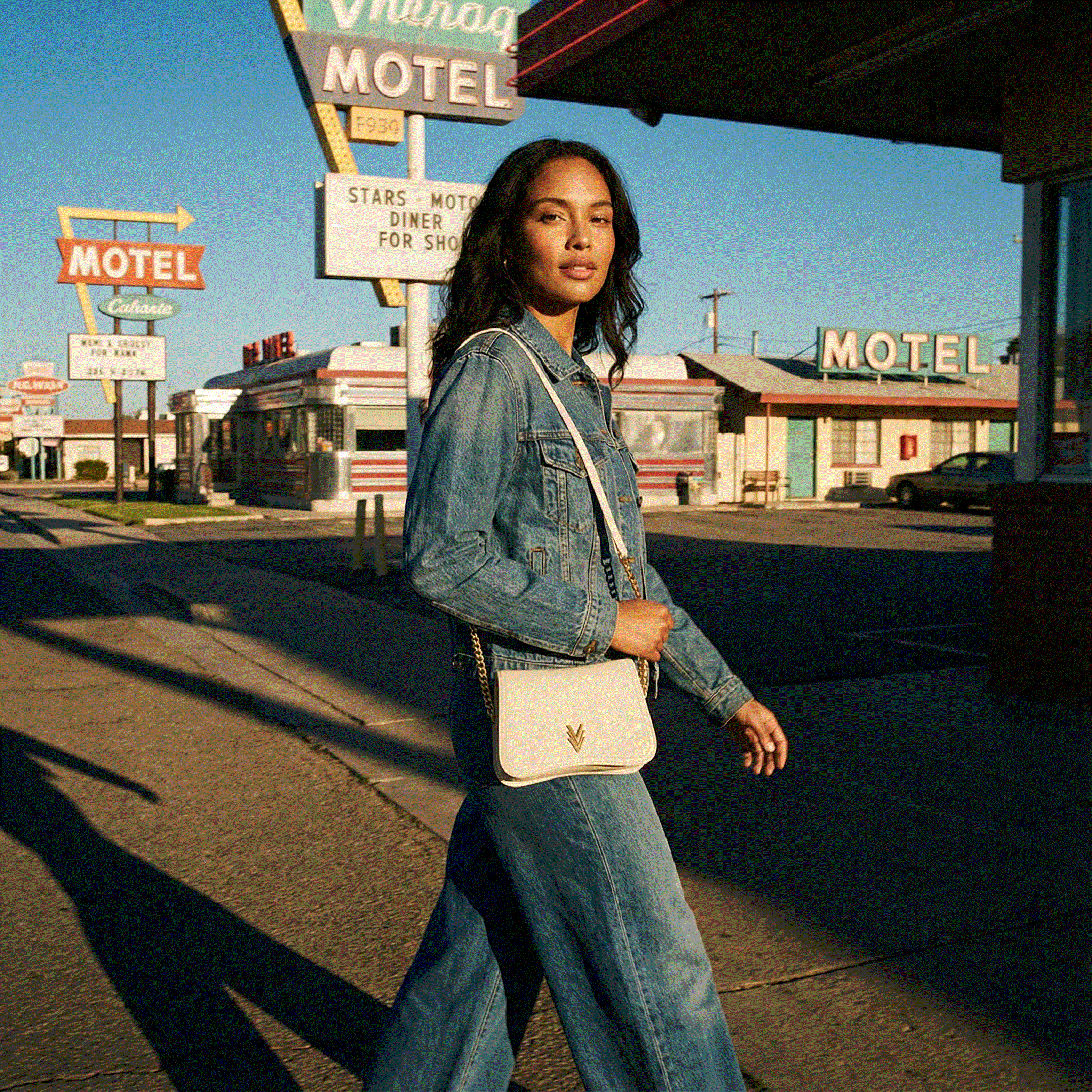 Woman walking in front of a motel with vintage signs.