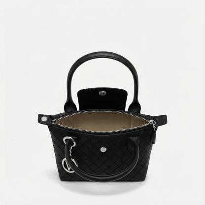 Black quilted handbag with gold hardware on a light gray background