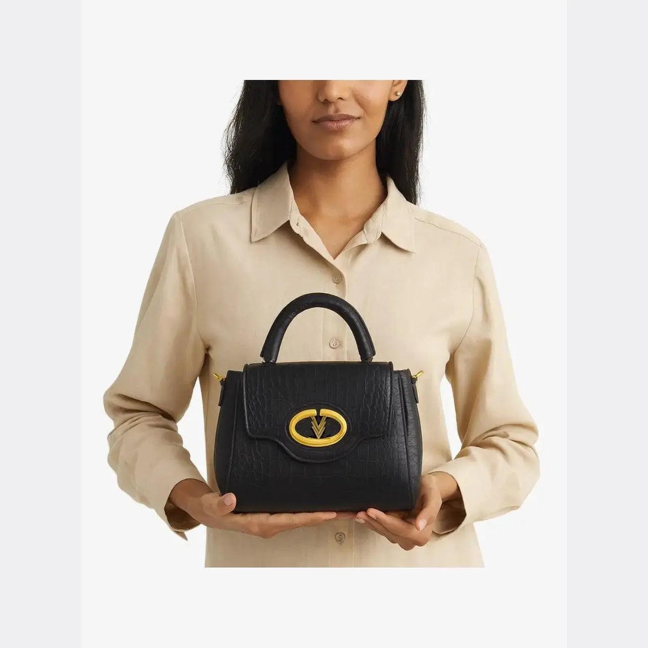 Woman holding a black handbag with a gold emblem against a white background