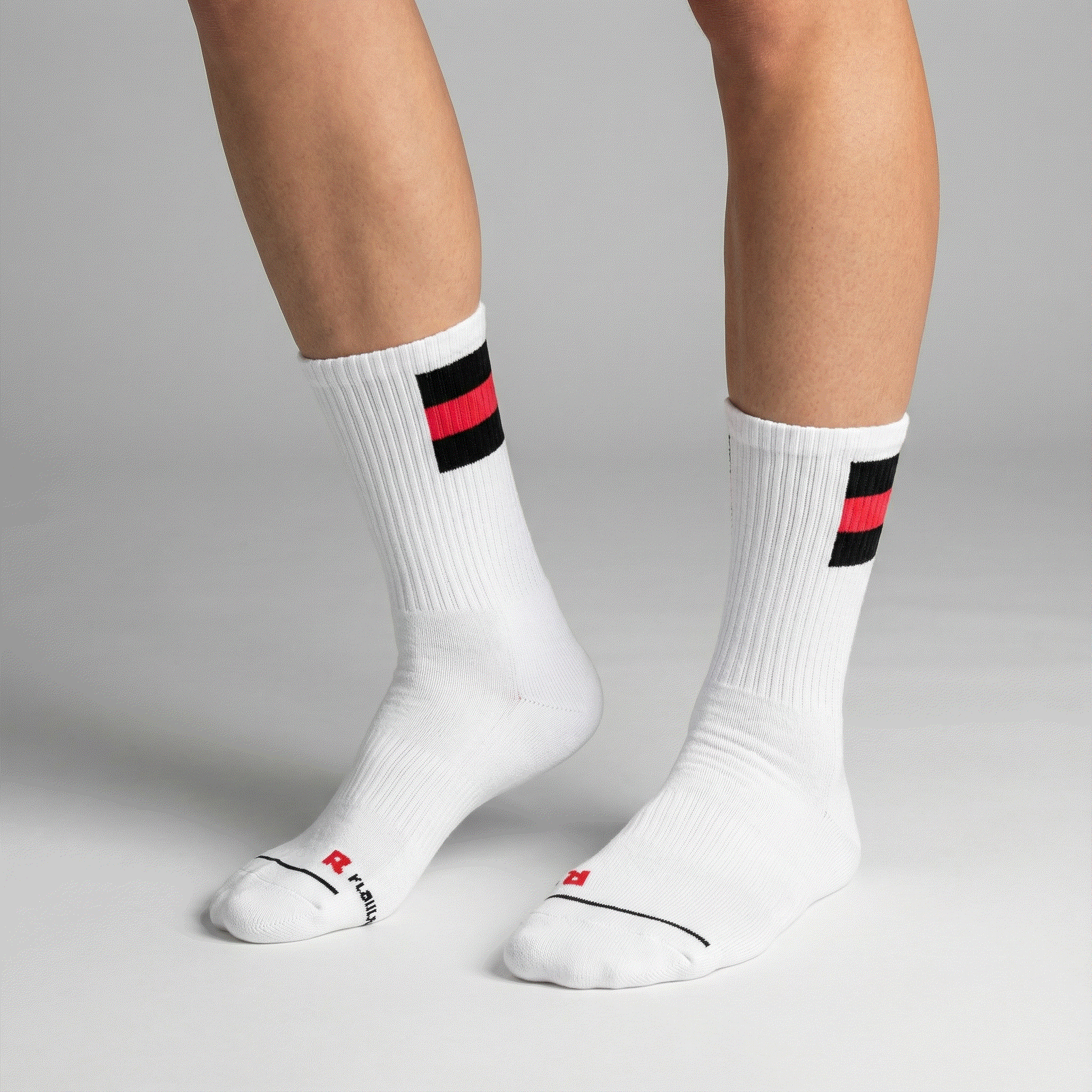 White socks with black and red stripes worn by a person on a gray background