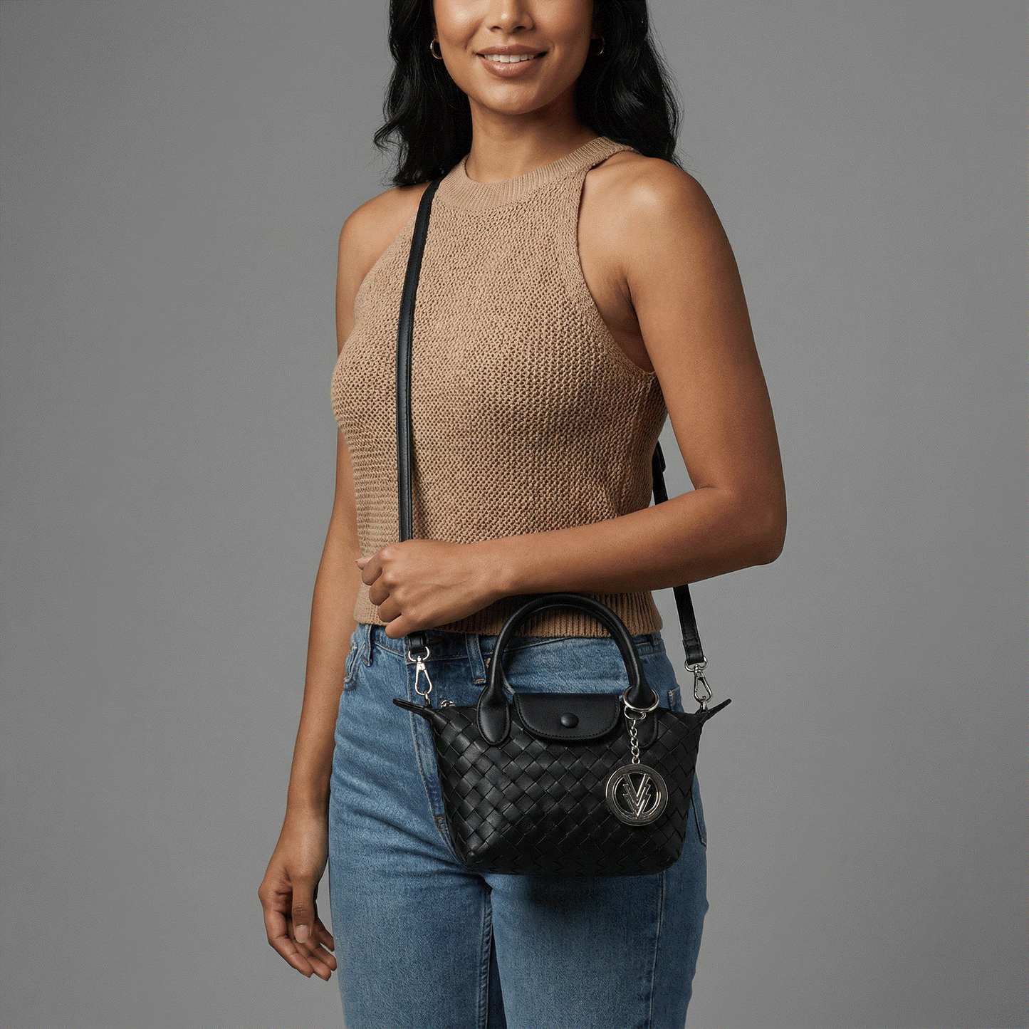 Woman holding a black handbag with a gray background