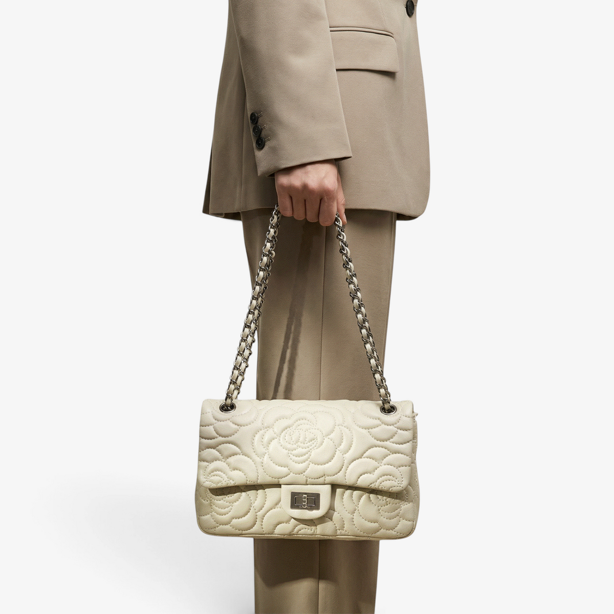 VAGOSHOPS Chiara Quilted Bag in bone leather with a silver chain strap held by a person in a matching beige suit.
