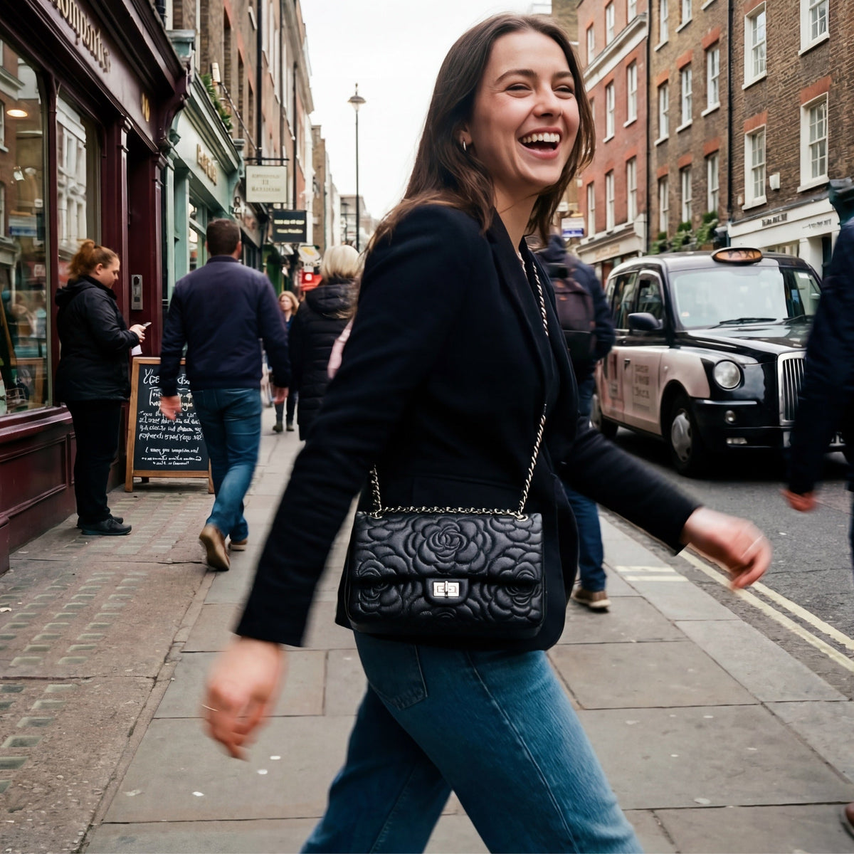 VAGOSHOPS Chiara quilted black leather bag with silver chain strap worn by a smiling woman on a city street.