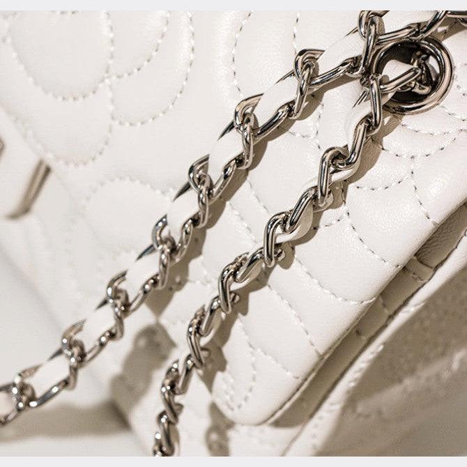 Close-up of a white quilted handbag with a silver chain detail.